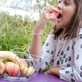 a woman sitting at a table eating an apple