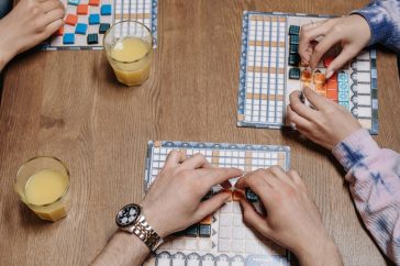 Close-up of hands and board game tiles during a fun gaming session indoors.